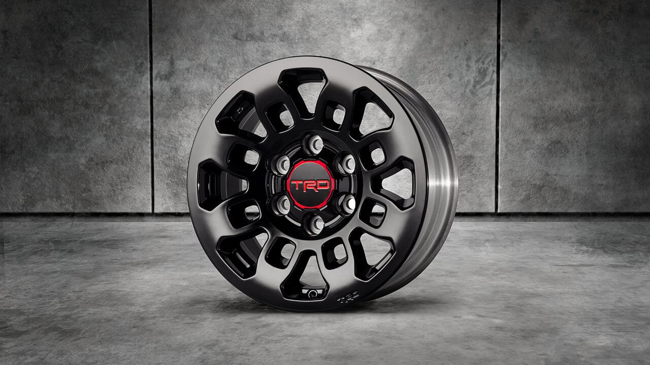 A shiny black Toyota Racing Development 16-inch alloy wheel stands on its side. 