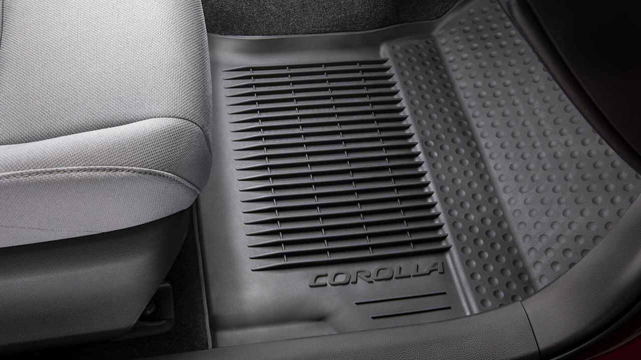 A black weather mats fits snugly in the floor space of a Corolla cabin.