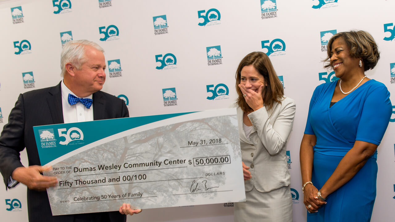Dumas Wesley representatives smile as JM Family’s Chairman of the Board Colin Brown presents them with a $50,000 donation in honor of the company’s 50th anniversary in 2018.