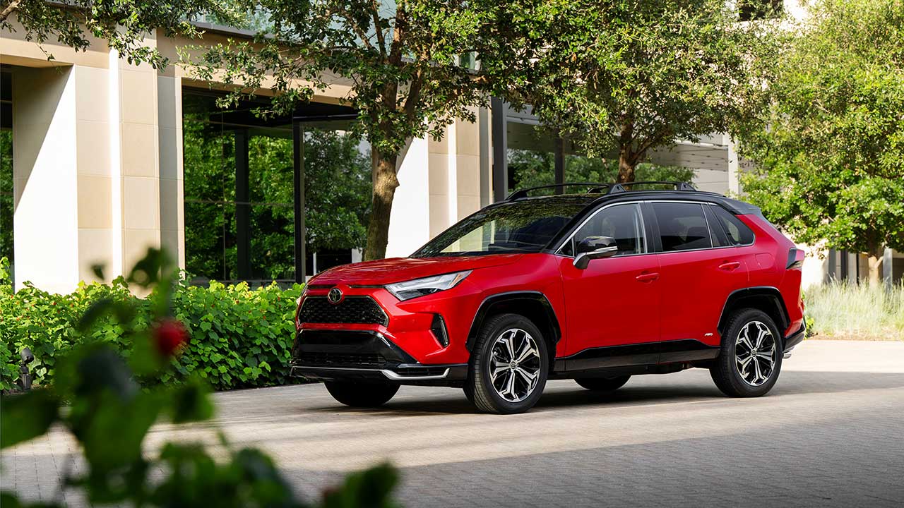 Bright red 2025 Toyota RAV4 outside an office building with vegetation