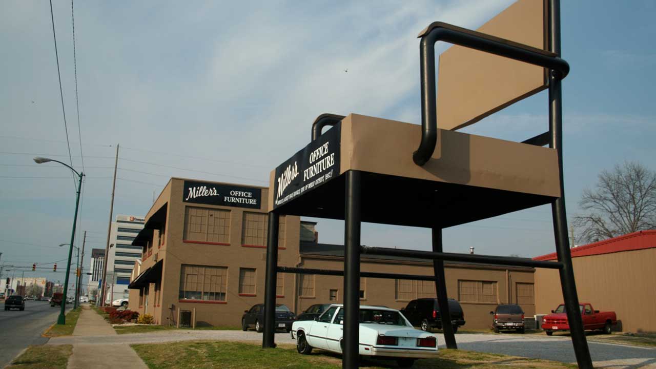 GIANT CHAIR IN A PARKING LOT COVERING A CAR