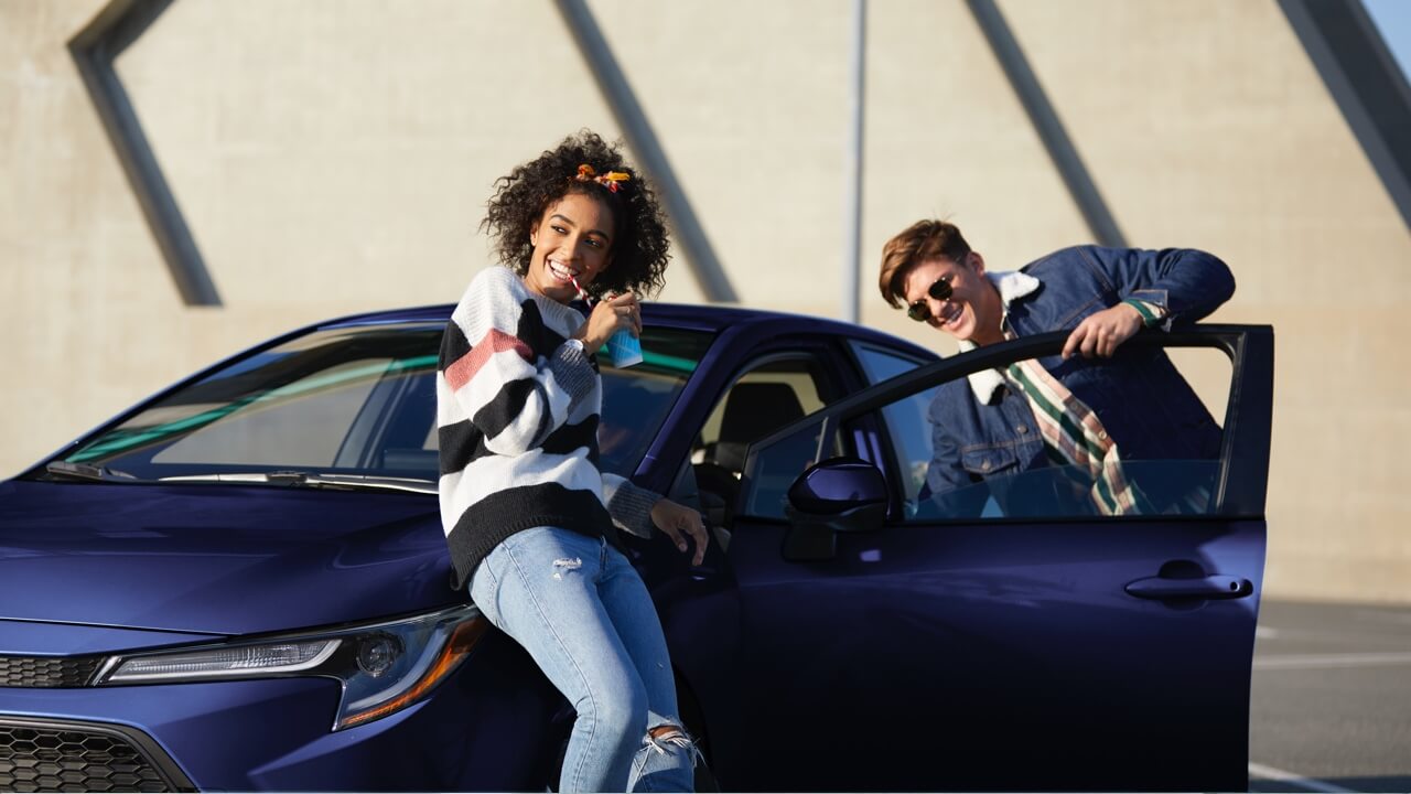 2020 Corolla with young couple leaning on vehicle