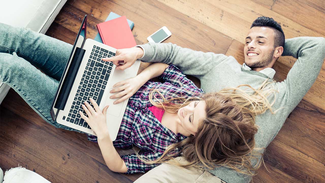 couple online with laptop laying on floor