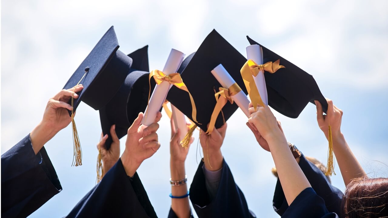 College grads holding caps up