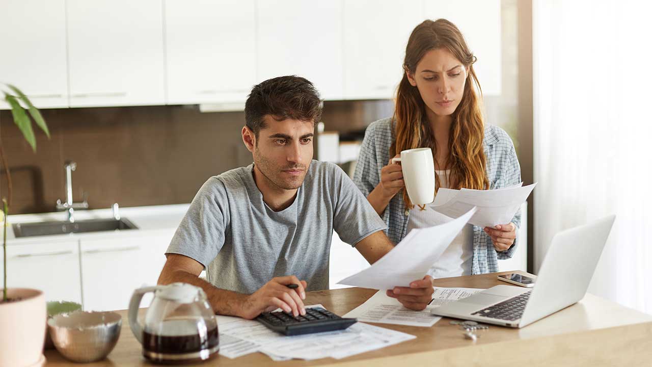 Couple paying bills online sitting at kitchen counter